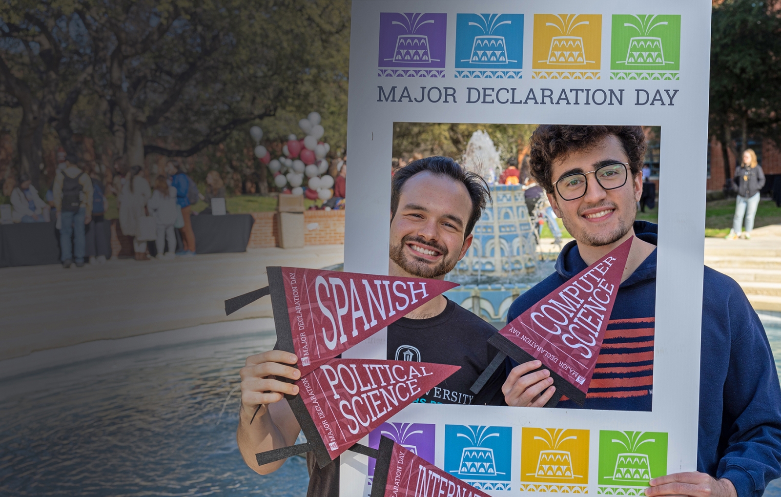 Blaine Martin and Caleb Aguiar pose in front of the fountain with a Major Declaration Day frame