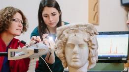 ԰ professor and her student examine an ancient sculpted bust.