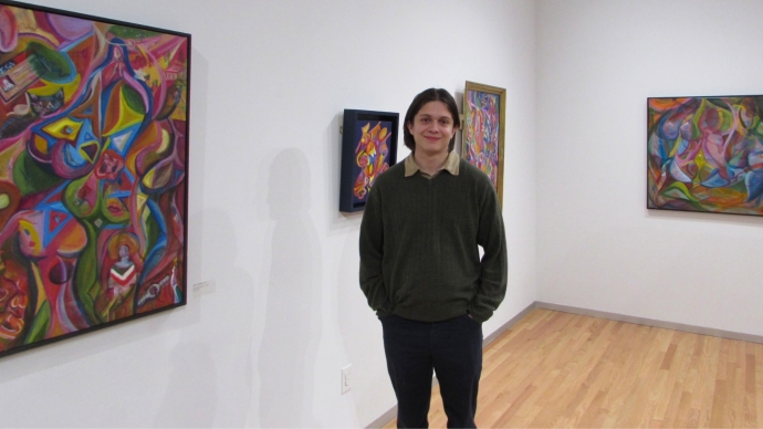 Pedro Acosta stands in gallery displaying his art