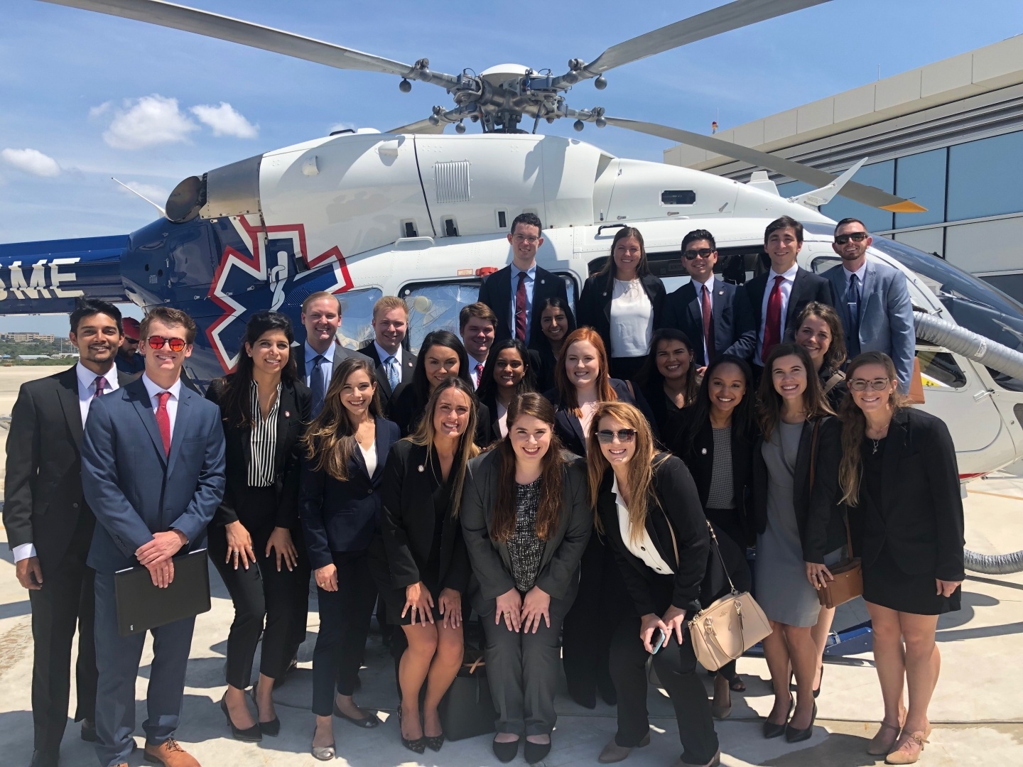 Graduate students gather in front of a rescue helicopter while visiting a local hospital.