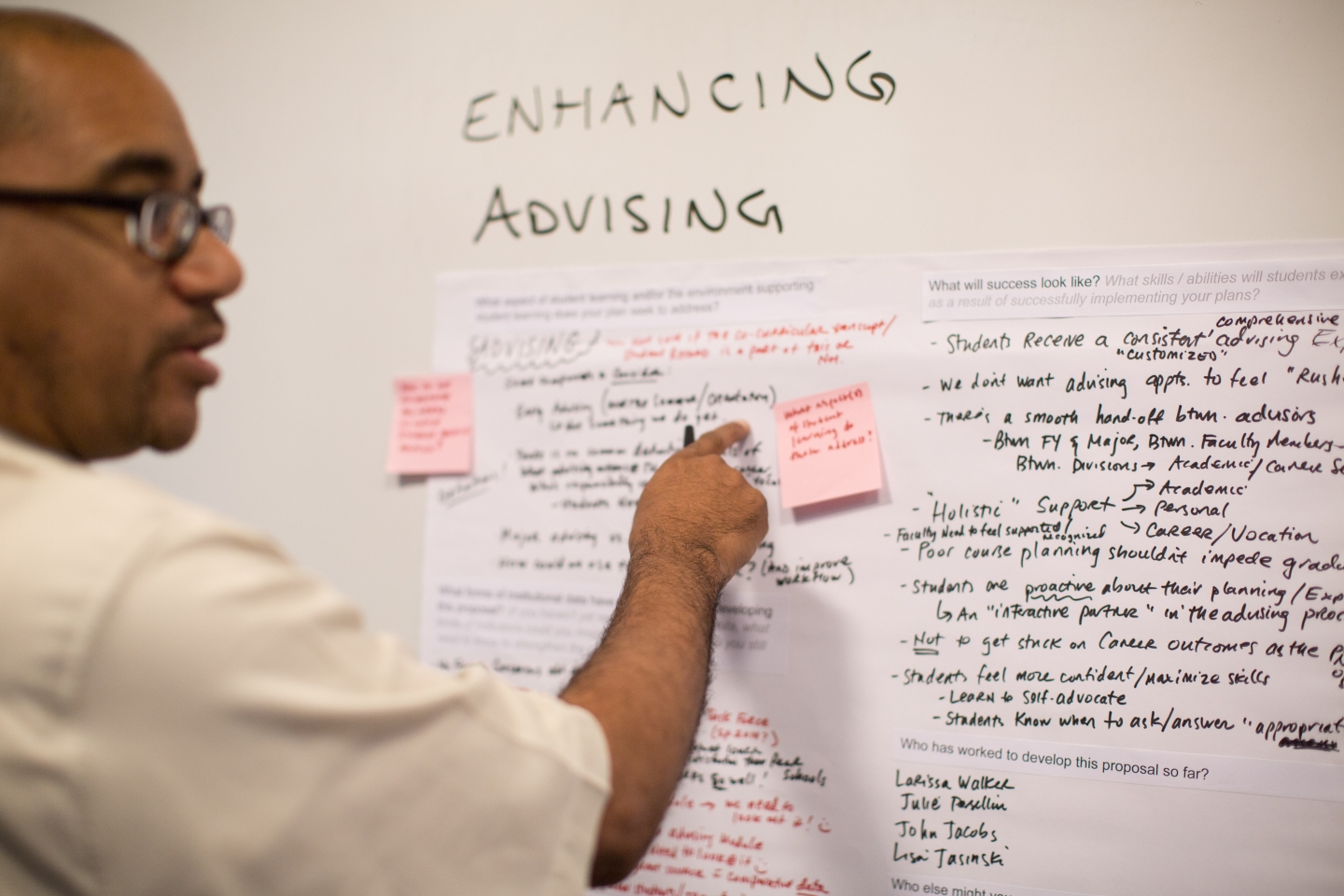 wilson terrell places a post-it note on a whiteboard about advising