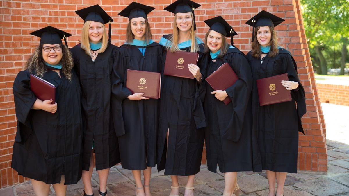 Graduation students in their caps and gowns holding their diplomas