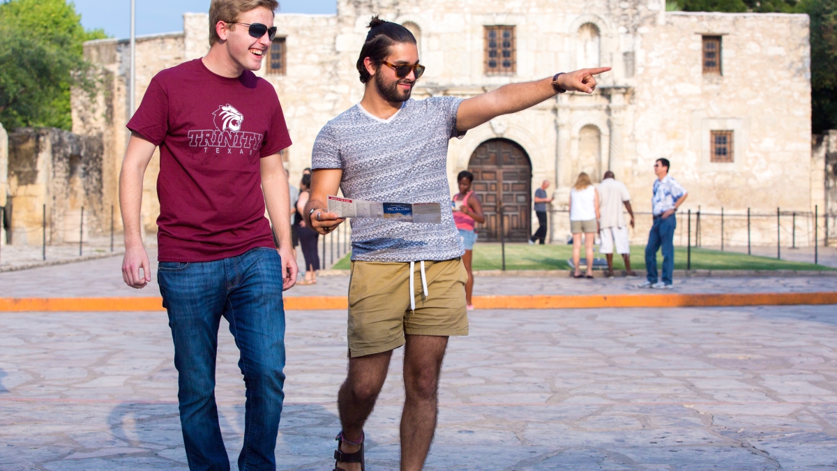 two students walk by The Alamo
